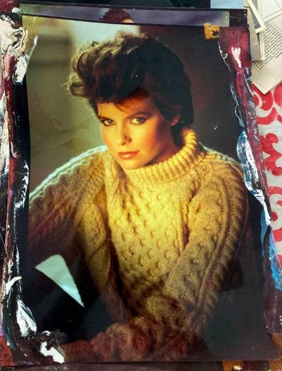 In an Aran sweater, by the window.