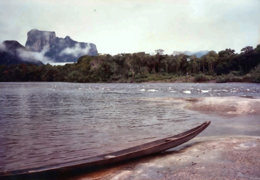 A table mountain across the river, with a dugout pulled up on the sand.